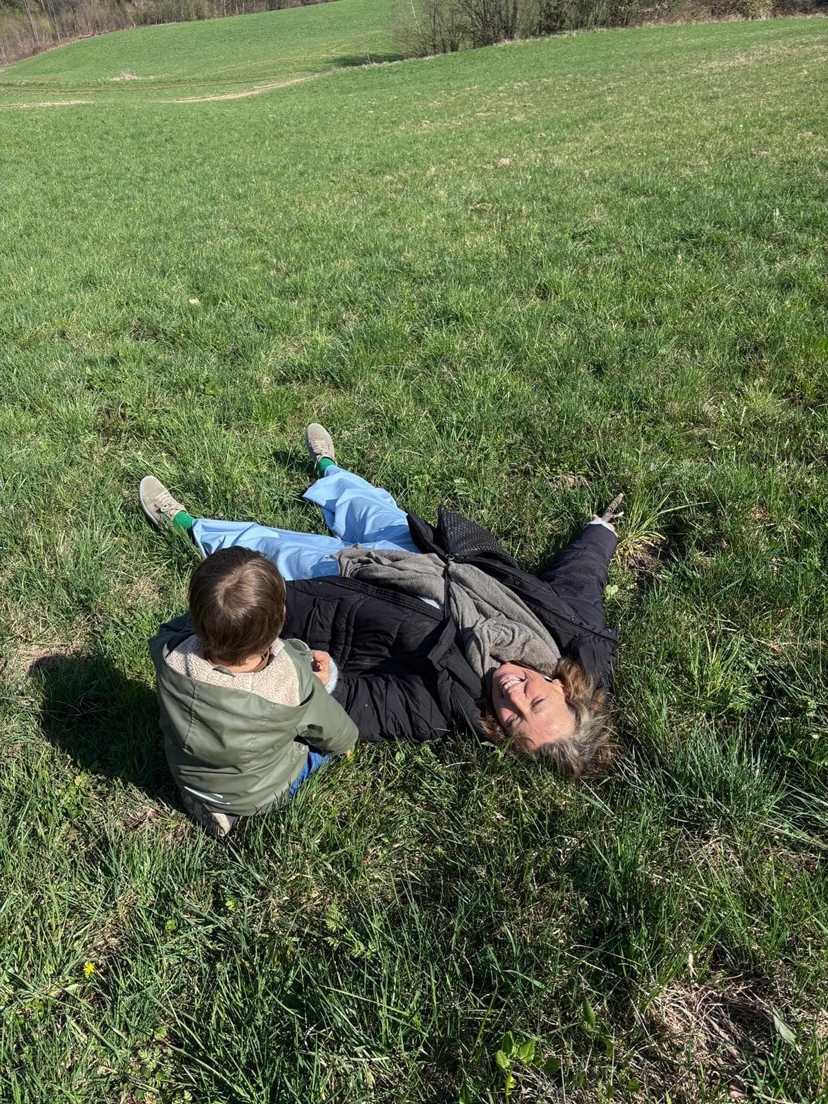 Beatrix lying in spring grass with her grandchild